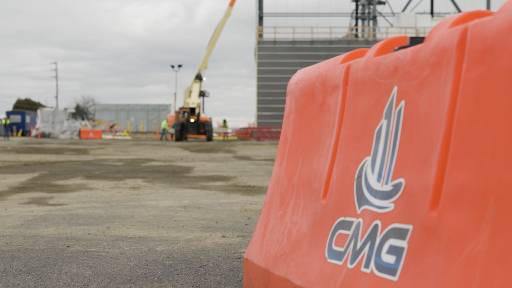 Orange CMG safety barrier at a job site with a lift in the background