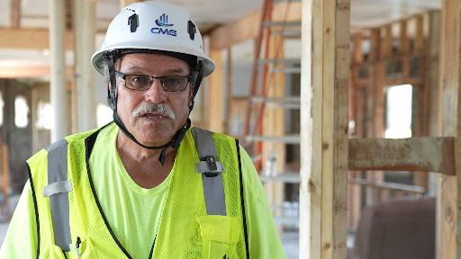 CMG crew member in a hard hat and safety vest at the Jim Ringo Field House project