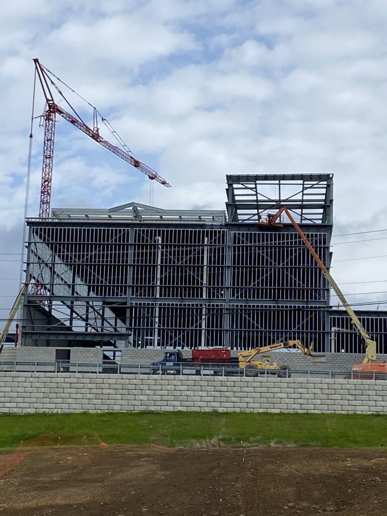 Steel frame of a large commercial building under construction with a tower crane