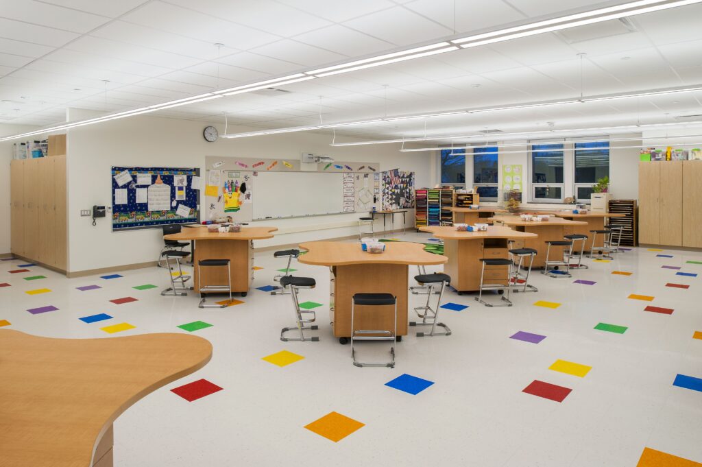 Elementary classroom with student tables and a colorful floor