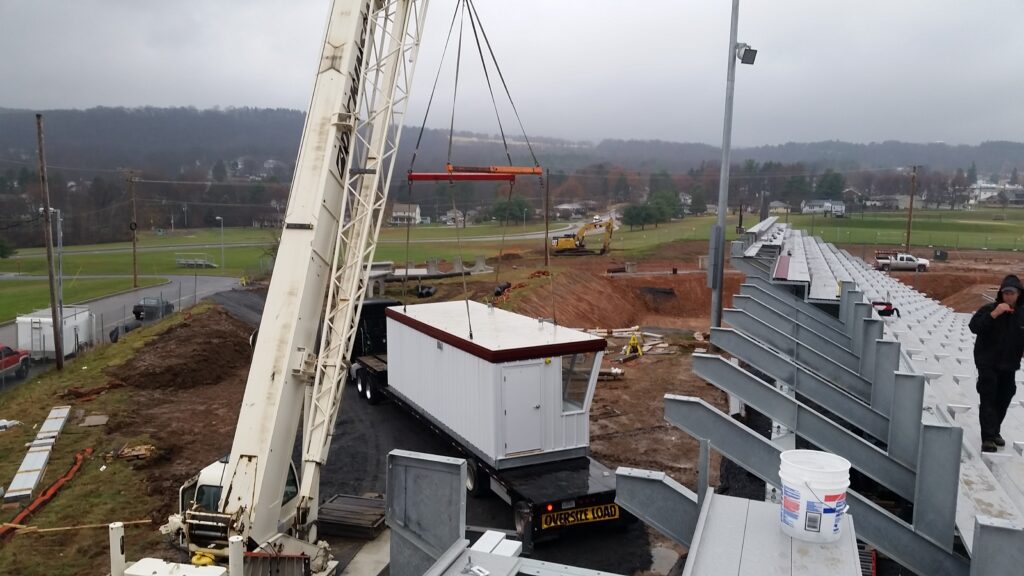 Crane setting bleachers at a school athletic field