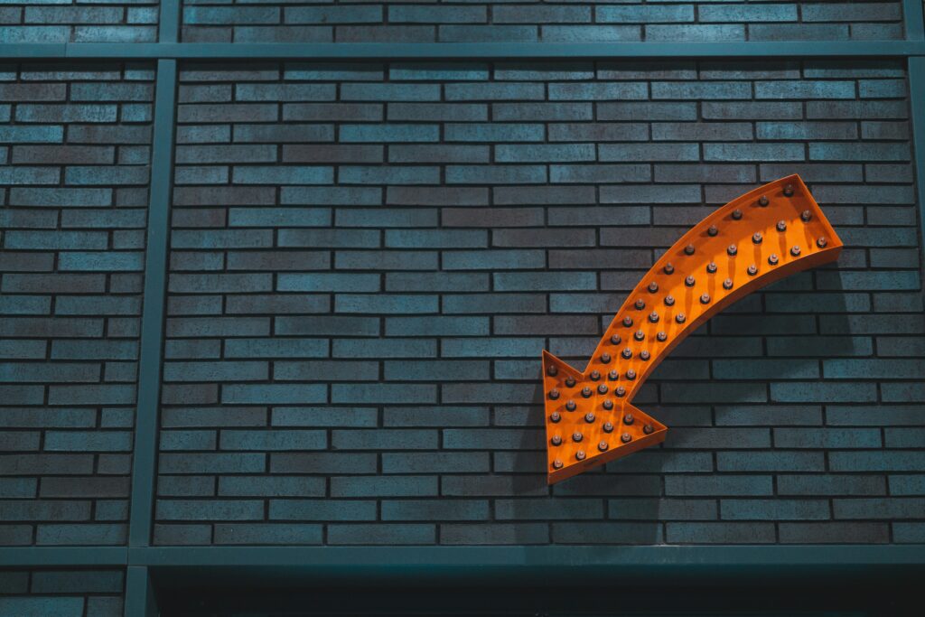 Orange arrow sign on a brick wall